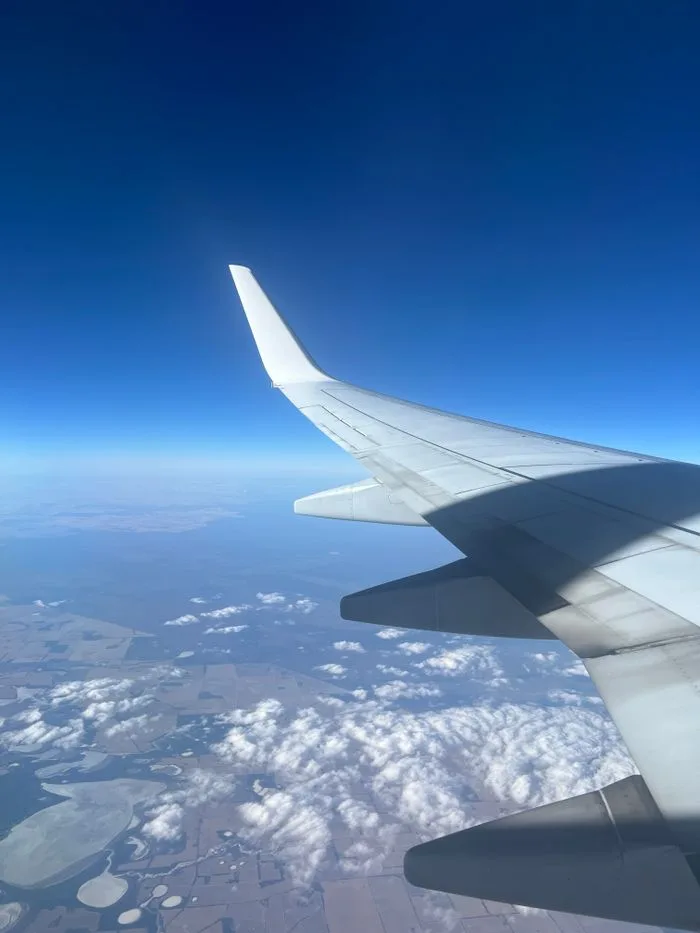 View from airplane window showing wing over Varley, Australia, beneath clear skies.
